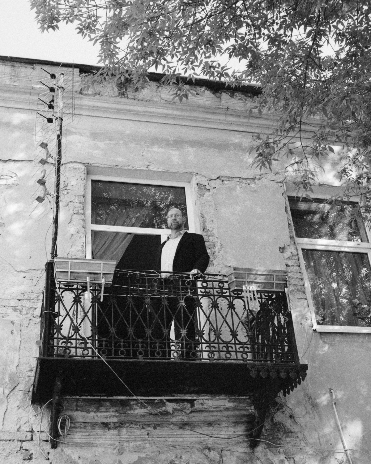 Ruth's son looks out from a wrought iron balcony of the old Ger synagogue, the plaster fallen away to brick around the windows.